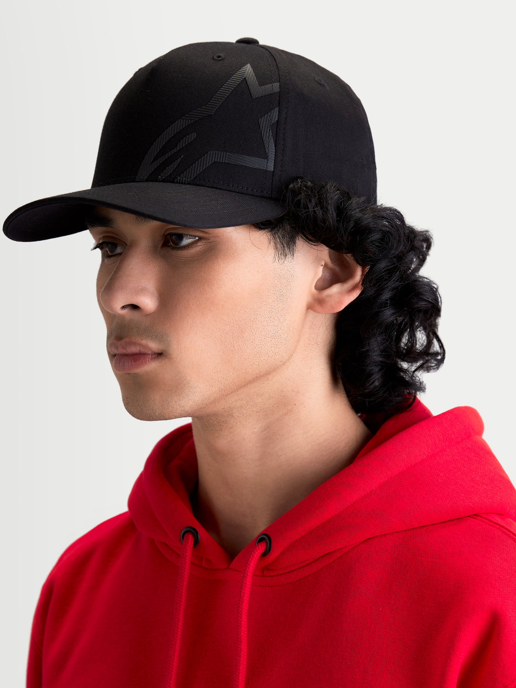 Alpinestars Maze keps, svart motorsportinspirerad sportswear-keps för herr med strukturerad krona, böjd skärm och texturerad Astars Corp Shift-logotyp, profilvy på modell.