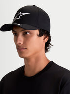 Alpinestars Arclight keps, svart och vit sportswearkeps med böjd skärm, strukturerad krona och vit texturerad Astars-logotyp i pufftryck, visas på modell.