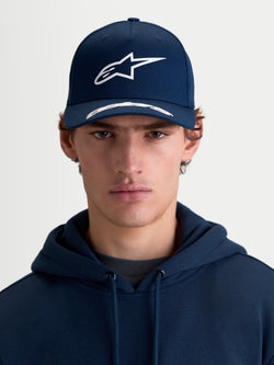 Alpinestars Arclight keps, sportkeps med böjd skärm, marinblå och vit, frontvy på modell, med strukturerad krona, texturerad pufftryckt Astars-logotyp och premium bomullstwill.