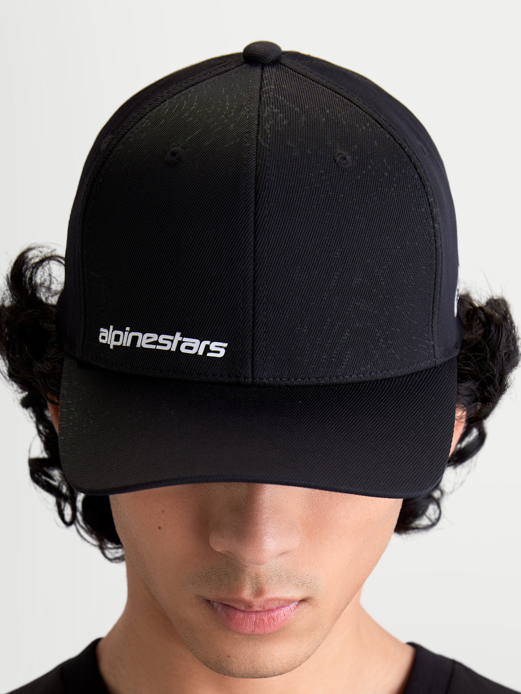 Alpinestars Points Hat, Black Curved Bill Sportswear Cap on Model, featuring White Alpinestars Word Logo on front, Lightweight Nylon Tactel Construction.