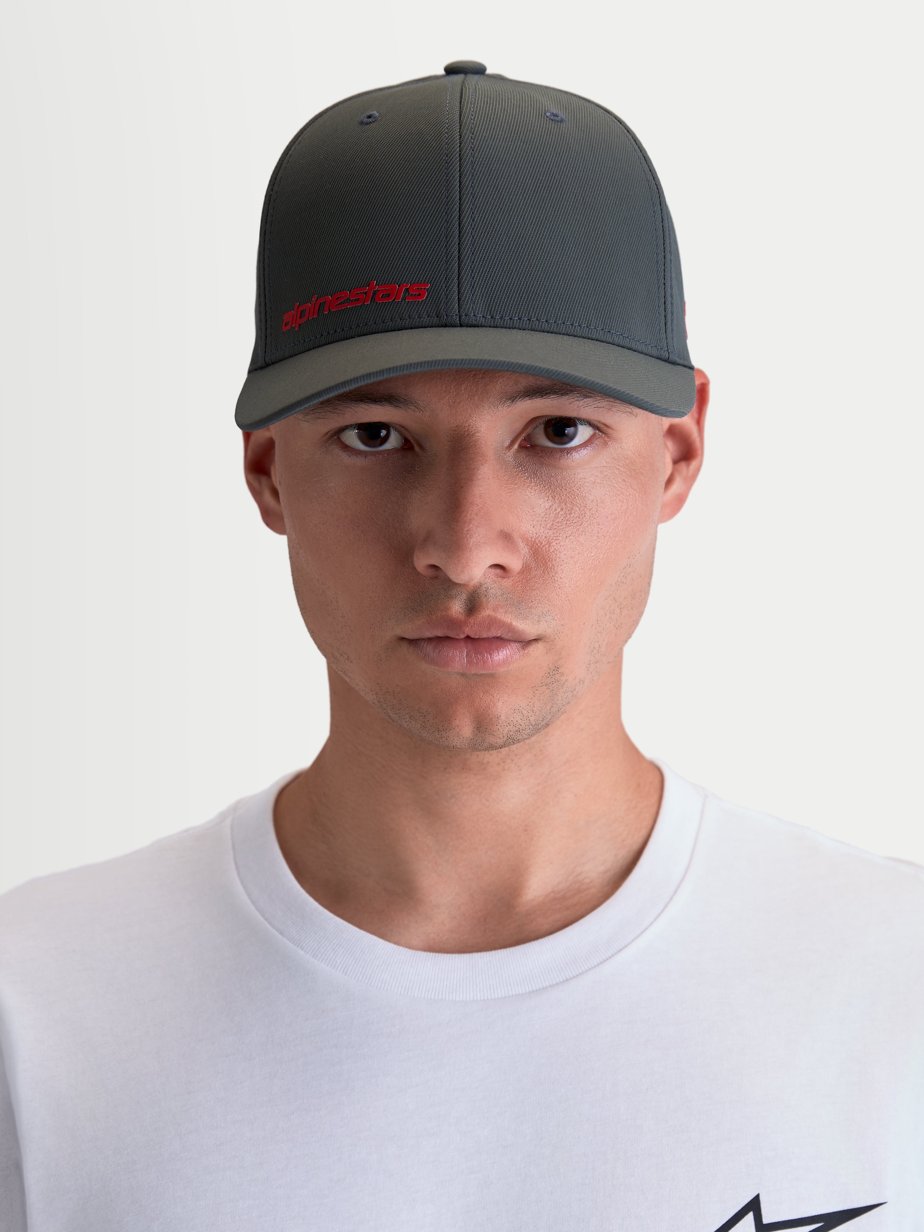 Alpinestars Points keps, sportkeps med böjd skärm för herr och dam, framifrån på modell, mörkgrå med röd Alpinestars-logotyp, lätt nylon tactel-material med flex-back-passform