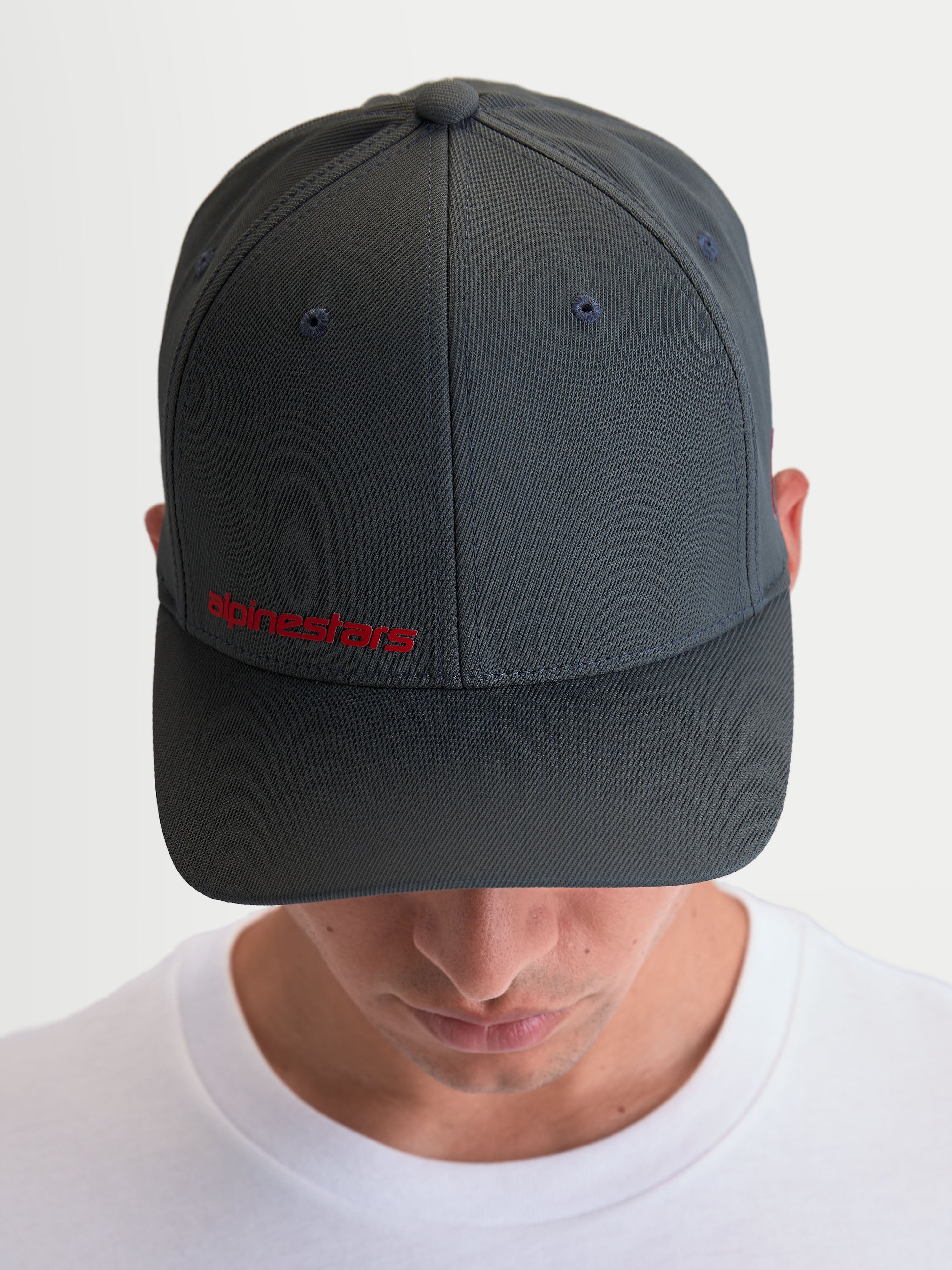 Alpinestars Points keps, mörkgrå sportkeps för herrar med böjd skärm och röd Alpinestars-ordlogotyp framtill, tillverkad i lätt nylontactel för vardaglig motorsportstil.