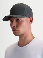Alpinestars Points keps på modell, mörkgrå sportkeps med böjd skärm och röda logotyper, tillverkad i lätt nylon tactel med flex-back-passform för vardagsbruk.