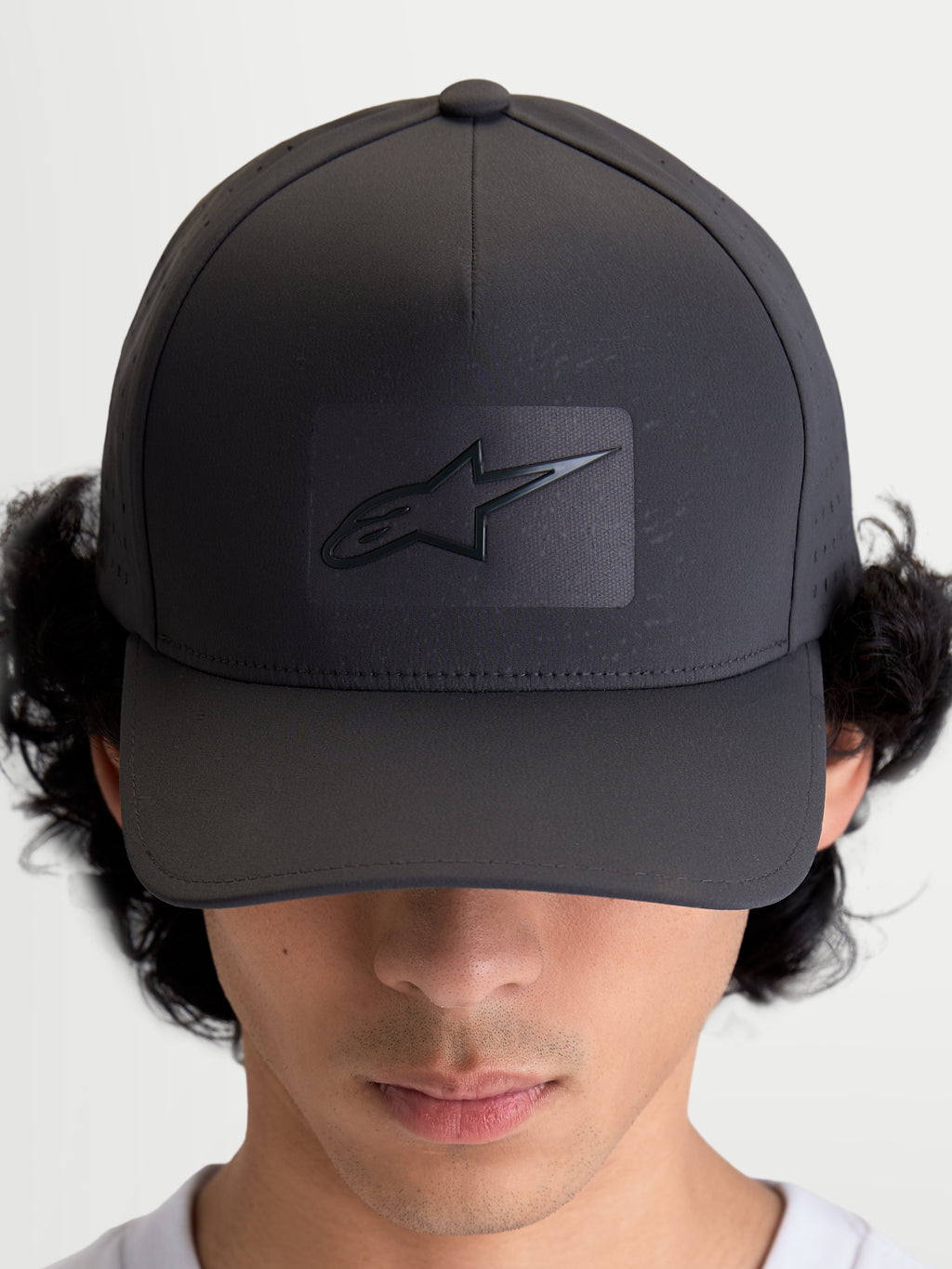 Alpinestars Algo Perf Adjustable keps, mörkgrå sportkeps för vardagsbruk med böjd skärm, strukturerad krona och sonic-weldad Astars-logotyp, sidoperforeringar för luftflöde, sedd framifrån på modell.