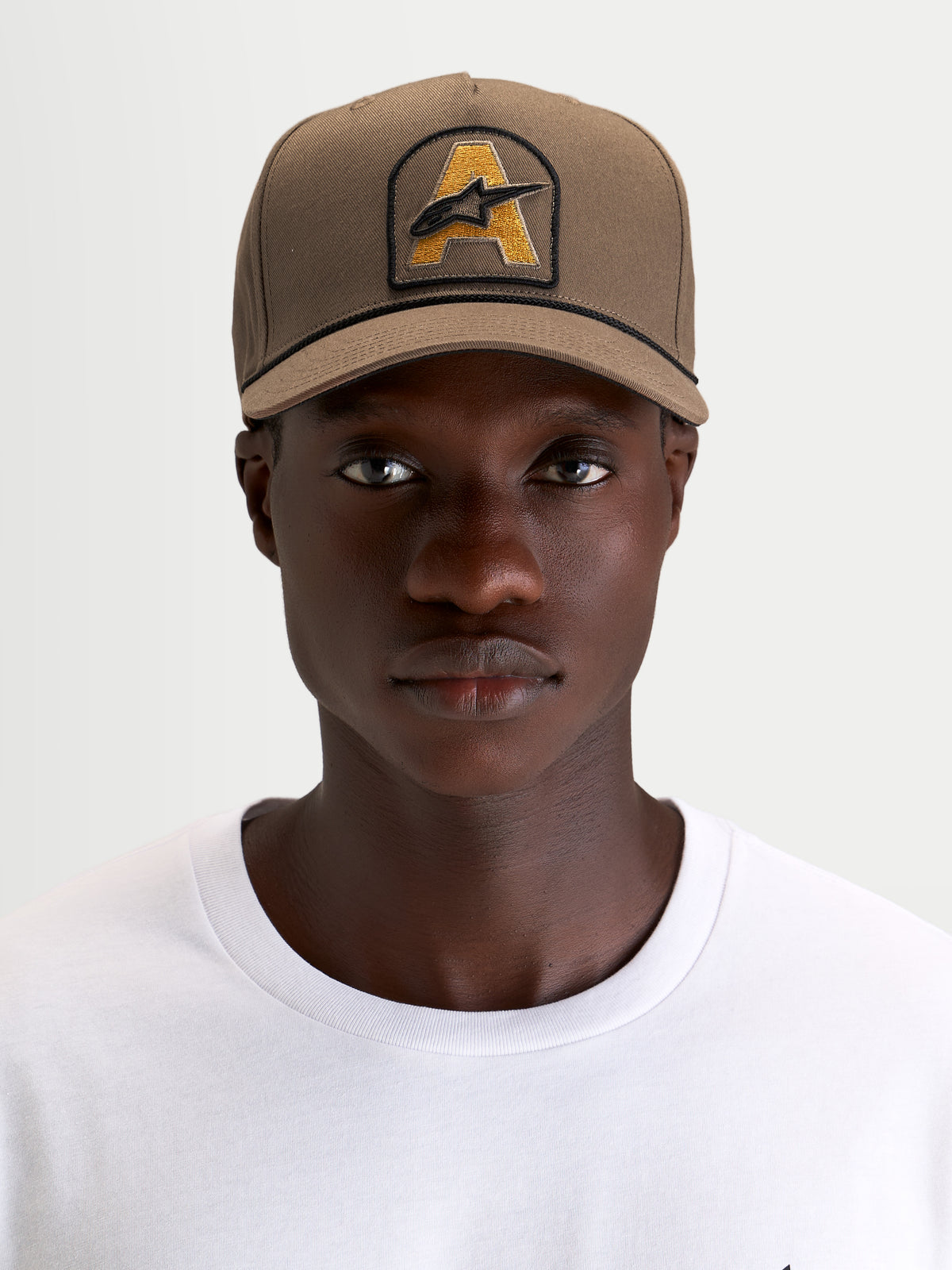 Alpinestars Acme Snapback keps, brun keps med strukturerad krona och böjd skärm, broderad Astars-logotyp med repkant, bärs av en modell