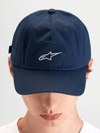 Alpinestars Dylan Dad Keps, blå keps i bomullstwill med böjd skärm och broderad vit Astars-logotyp framtill, bärs av en modell