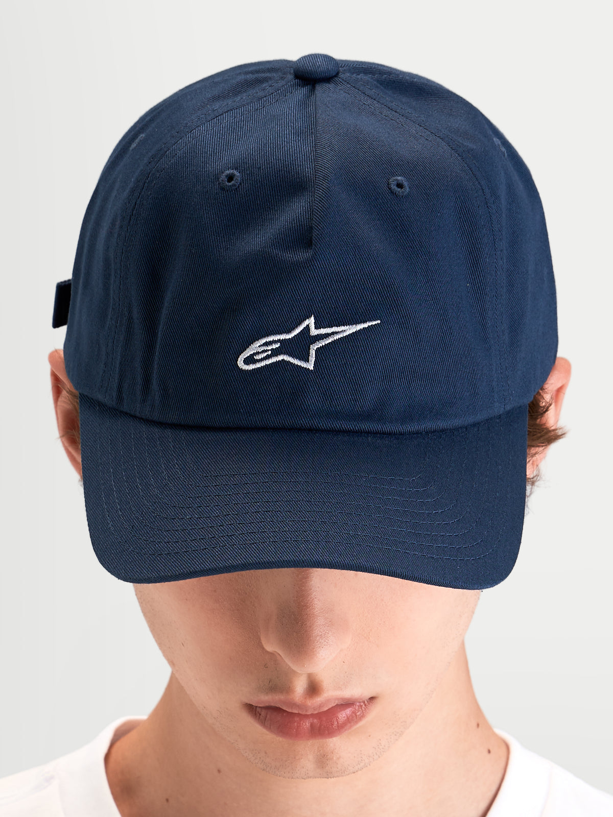 Alpinestars Dylan Dad Keps, blå keps i bomullstwill med böjd skärm och broderad vit Astars-logotyp framtill, bärs av en modell