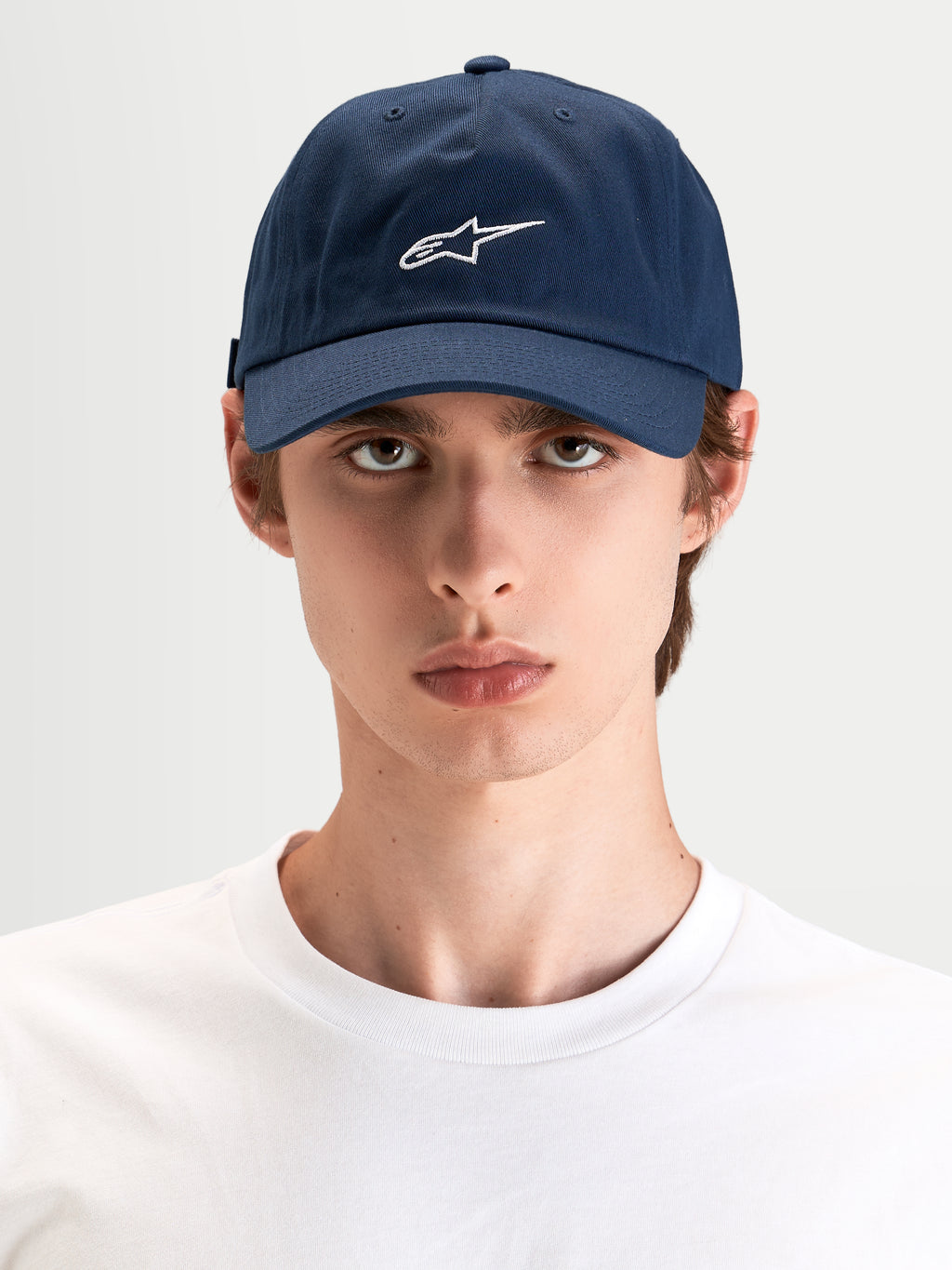 Alpinestars Dylan Dad Keps, marinblå keps med vit Astars-logobrodyr, böjd skärm och ostrukturerad låg krona, buren av en modell