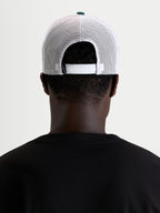 Alpinestars Baron Trucker Hat, casual sportswear mesh cap, worn by a model, rear view showing adjustable snapback closure and white poly mesh panels with green crown button