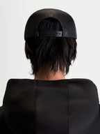Alpinestars Gravel keps, svart snapback-keps i unisex-modell, sedd bakifrån på en modell som visar den andningsbara baksidan i mesh och justerbart snäppspänne.