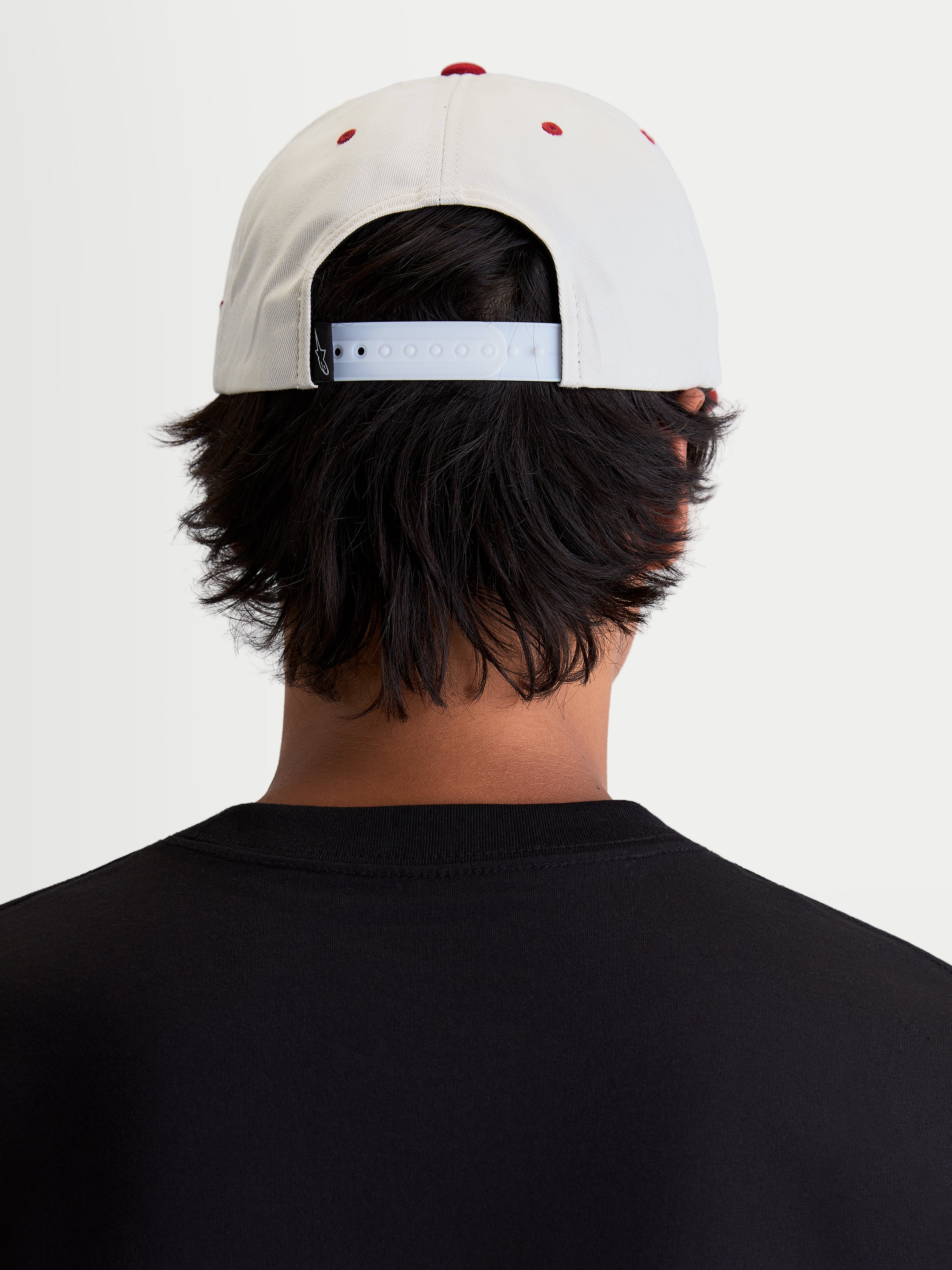 Alpinestars Stadium Snapback keps, vit och röd livsstilskeps, har en justerbar snapback-knäppning och strukturerad krona, bild bakifrån på modell som visar passform för en motorsportinspirerad vardagsstil.