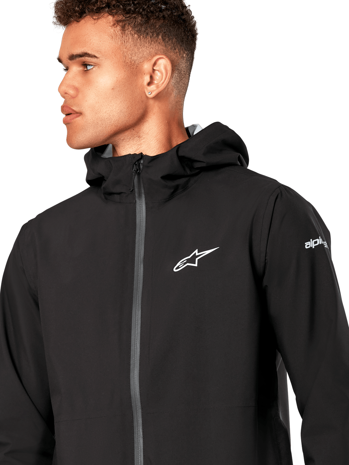 Alpinestars Kascade regnjacka, svart skaljacka för regn, med vit stjärnlogotyp på bröstet, fast huva och belagd omvänd spiraldragkedja framtill, avslappnade motorsport-inspirerade ytterkläder