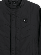 Alpinestars Precedent Jacka, quiltad sportswearjacka, svart, närbild som visar ett ikoniskt vinklat quiltmönster, låg ståkrage, täckt dragkedja framtill och ett litet logomärke på bröstet