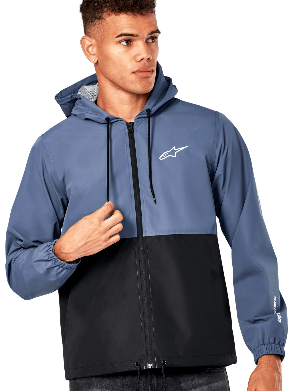 Manlig modell i Alpinestars Speeder vindjacka, blockfärgad design i skifferblått och svart, huva med svarta dragsnören, vit logotyp på bröstet, avslappnad motorsportinspirerad vindjacka