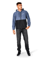 Alpinestars Speeder vindjacka, skifferblå och svart, lättviktsjacka med huva och meshfoder, vit stjärnlogotyp på bröstet, bärs med svarta jeans och sneakers, vardaglig motorsport-streetwear-design
