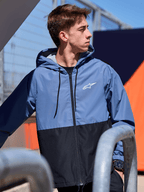Alpinestars Speeder vindjacka, lätt vindjacka med huva, blockfärgad design i skifferblått och svart, vit Alpinestars-logotyp på bröstet, meshfodrad med huva med dragsnöre, avslappnad motorsport-inspirerad streetwear