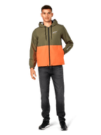 Alpinestars Speeder Windbreaker Jacket, blockfärgad i militärgrönt och orange, lätt jacka med huva, svarta dragsnören och dragkedja framtill, vit logotyp på bröstet och ärmen, bärs med mörka jeans och svarta sneakers, avslappnad sportstil.
