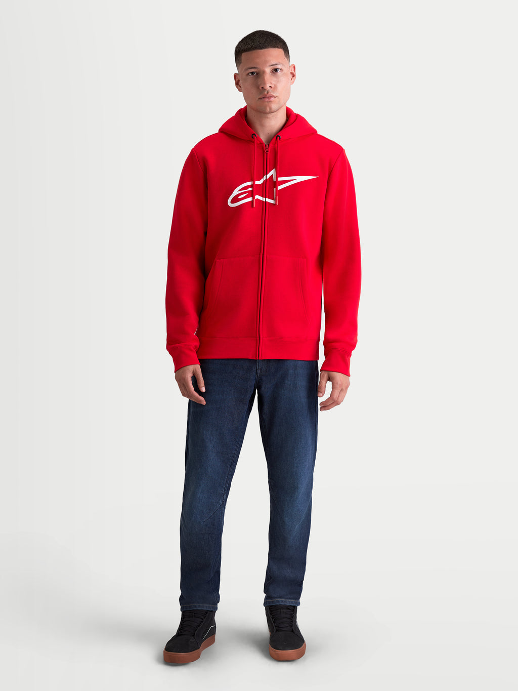 Alpinestars Ageless Zip V3 huvtröja, röd och vit herrhuvtröja i sportswear-fleece med dragkedja, stor vit logotyp på bröstet, dold spiraldragkedja och ribbade muddar, framifrån på modell.