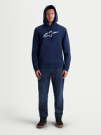 Alpinestars Ageless V3 huvtröja, marinblå fleecehuvtröja i unisex-modell med broderad vit Alpinestars-logotyp på bröstet, motorsport-lifestylekläder, modellbild i helfigur.