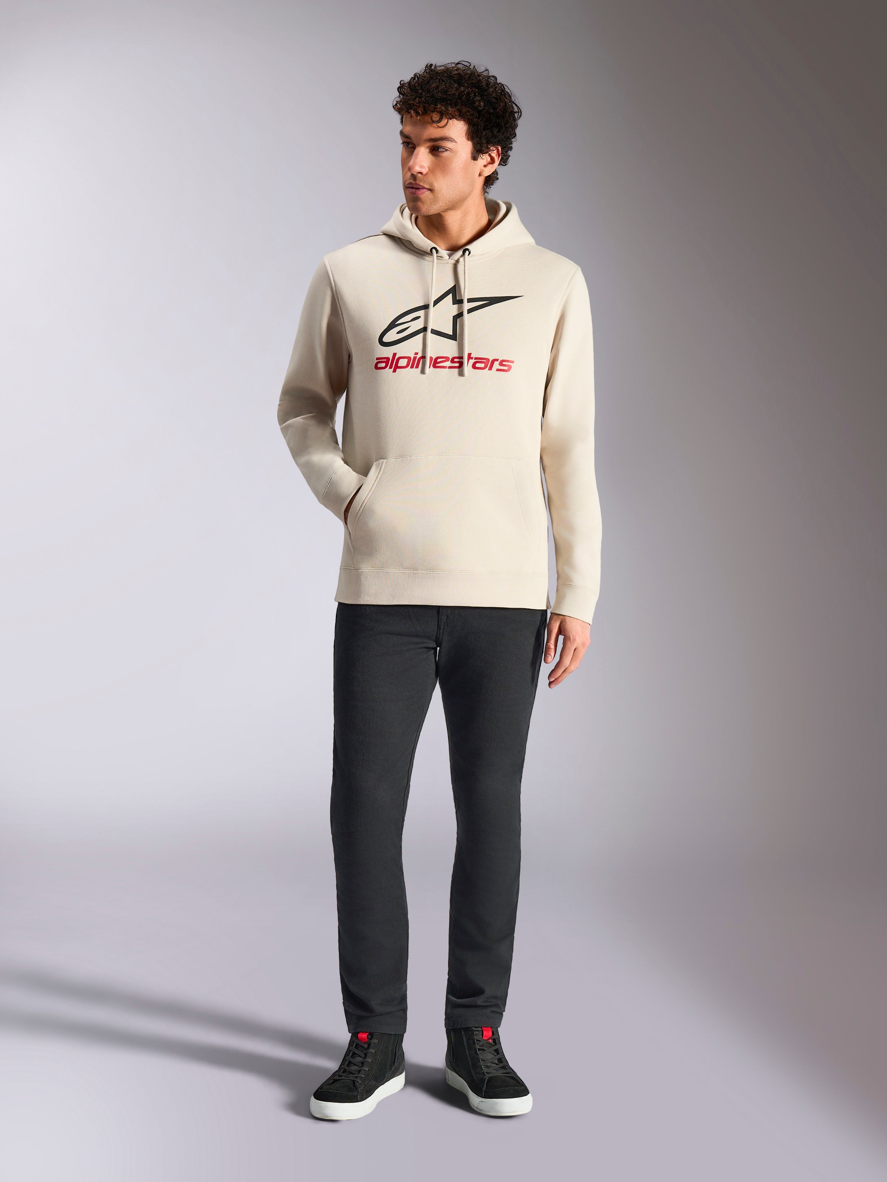 Alpinestars Always V3 Hoodie, casual streetwear, off-white with black star logo and red lettering, drawstring hood, long sleeves, worn by male model with black pants and black sneakers