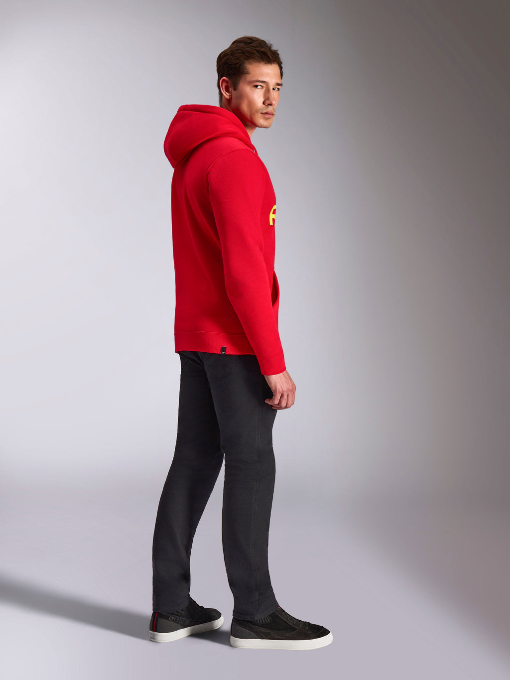 Alpinestars Ride V3 Hoodie, casual sportswear, Red with Hi-Vis Yellow branding, male model wearing red hoodie with black pants and sneakers, side profile view, pullover fleece design with ribbed cuffs and hem.