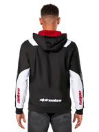 Alpinestars Sessions V3 Hoodie, baksida, svart med vita ärmpaneler och rött foder i huvan, med vitt ordmärke på ryggen och röd logotyp på ärmarna, vardaglig motorsportinspirerad streetwear