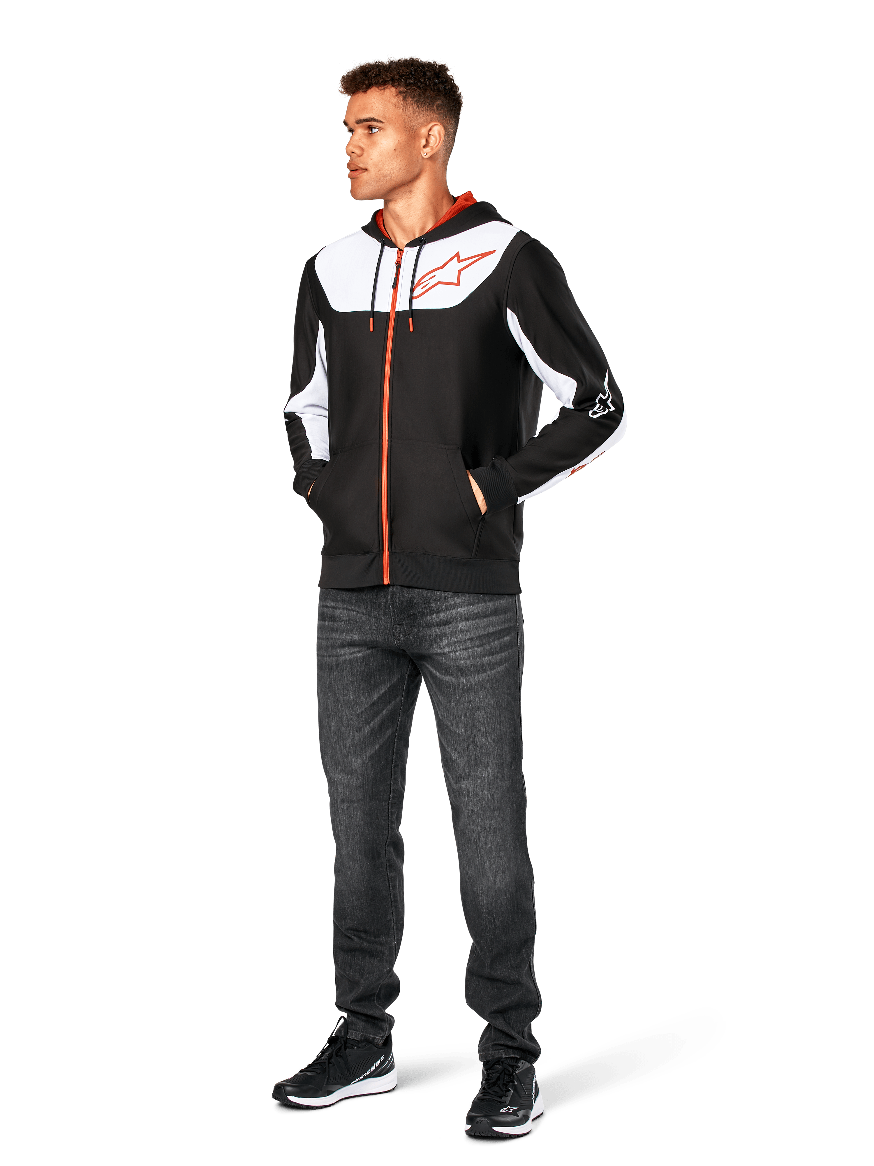 Alpinestars Sessions V3 Hoodie, vardaglig huvtröja med dragkedja fram, svart, vit och röd, bärs av en modell med mörka jeans och svarta sneakers, vita färgblockspaneler på bröstet och ärmarna, röda detaljer på dragkedja och dragsnören, stor bröstlogotyp, motorsportinspirerat streetwear i polyfleece