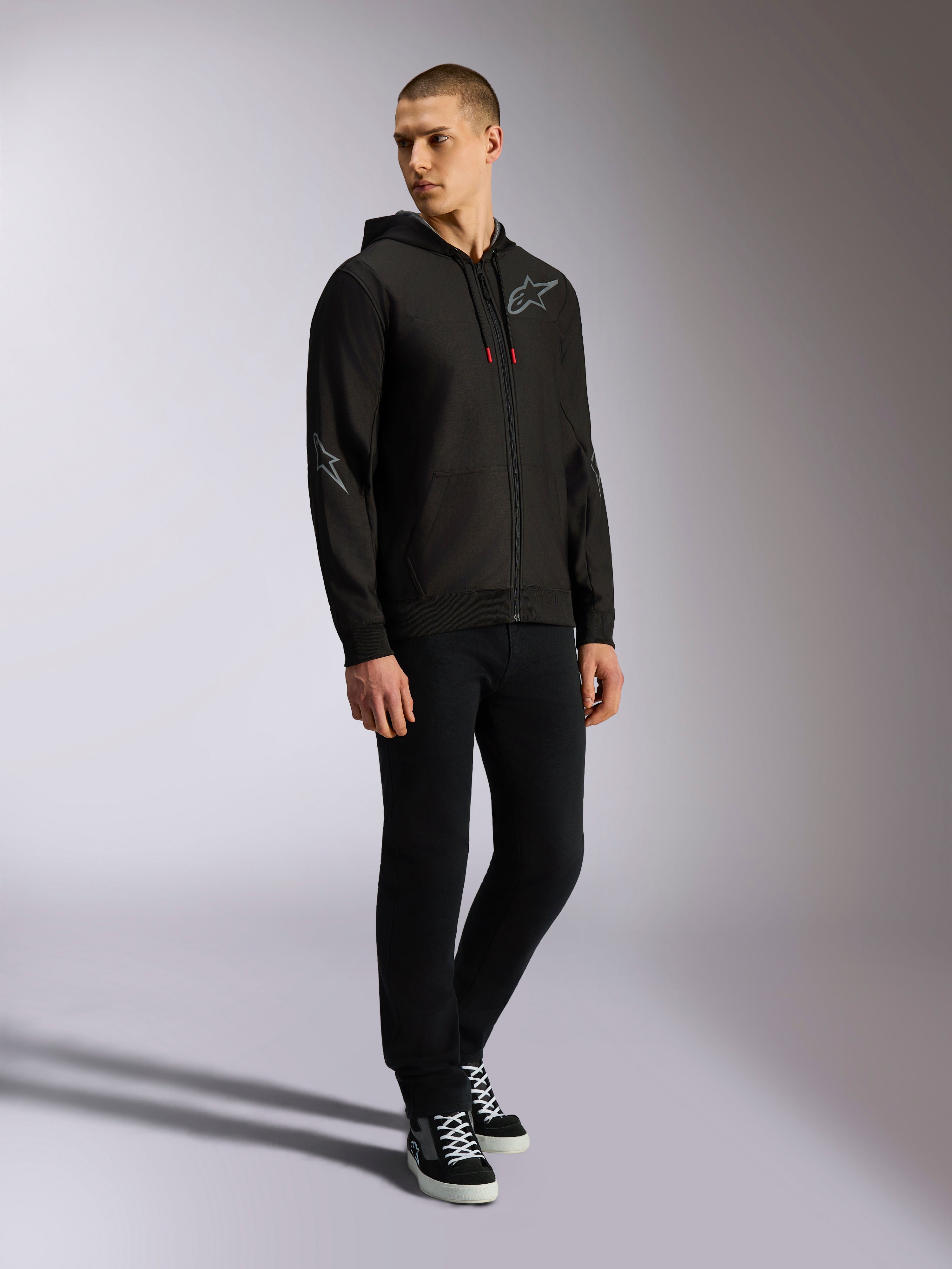 Alpinestars Sessions V3 Hoodie, zip front poly fleece, Black and Grey, grey chest and sleeve logos, drawstring hood with red-tipped drawcords, full-body view of model in casual motorsport streetwear