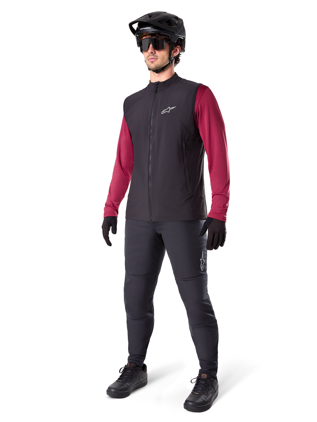 Alpinestars A-Dura Thermal Vest, svart cykelväst, bärs av en cyklist över en vinröd långärmad tröja och svarta byxor, med en svart MTB-hjälm och handskar, designad för mountainbike-cykling i kallt väder