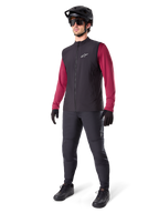 Alpinestars A-Dura Thermal Vest, svart cykelväst, bärs av en cyklist över en vinröd långärmad tröja och svarta byxor, med en svart MTB-hjälm och handskar, designad för mountainbike-cykling i kallt väder