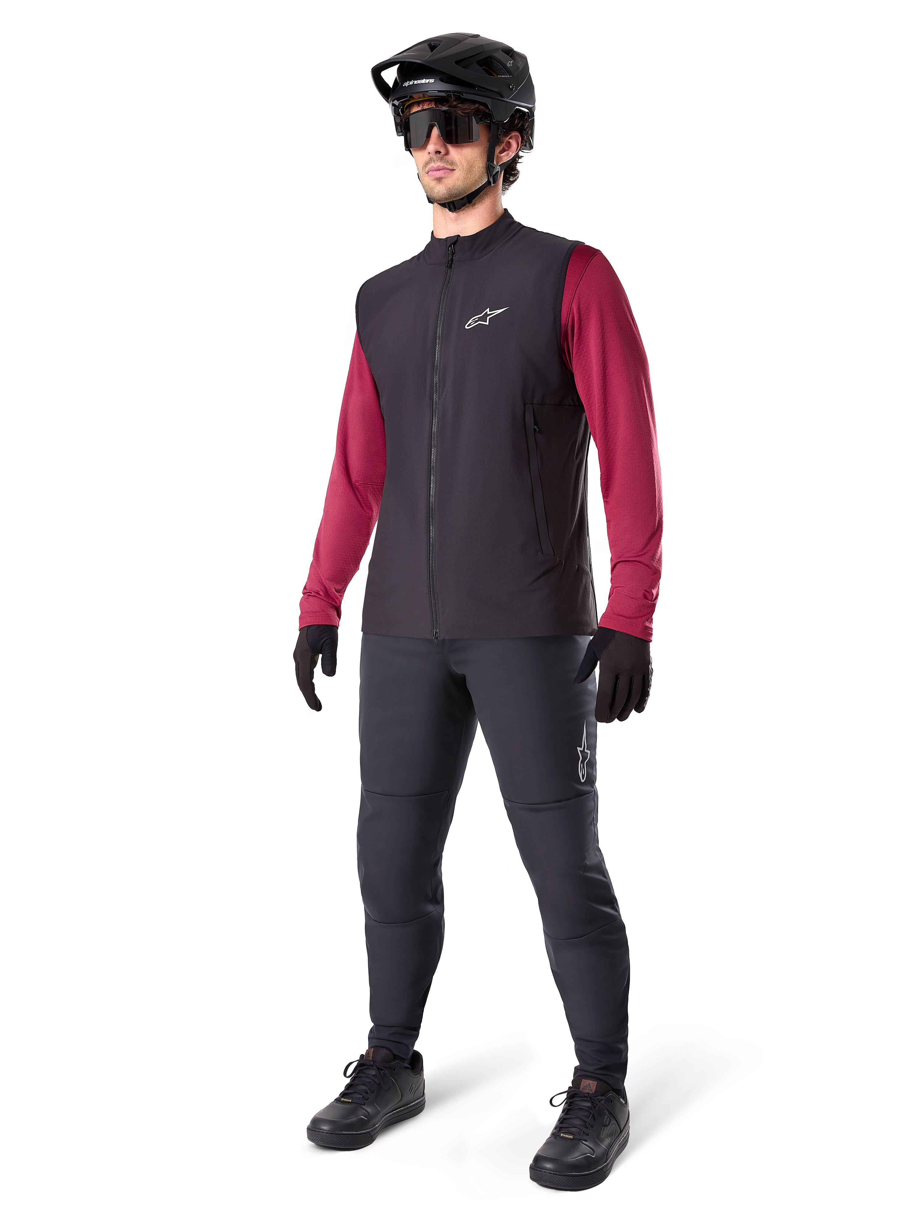 Alpinestars A-Dura Thermal Vest, svart cykelväst, bärs av en cyklist över en vinröd långärmad tröja och svarta byxor, med en svart MTB-hjälm och handskar, designad för mountainbike-cykling i kallt väder