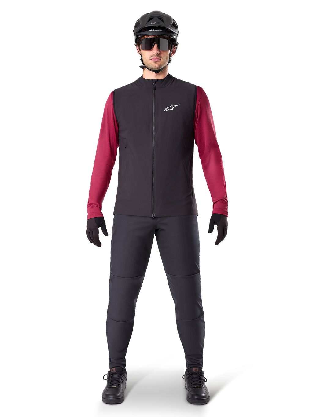 Alpinestars A-Dura värmeväst, svart cykelväst buren över en vinröd långärmad tröja, kombinerad med mörkgrå MTB-byxor, svart hjälm och solglasögon, teknisk mountainbike-utrustning för cykling i kallt väder