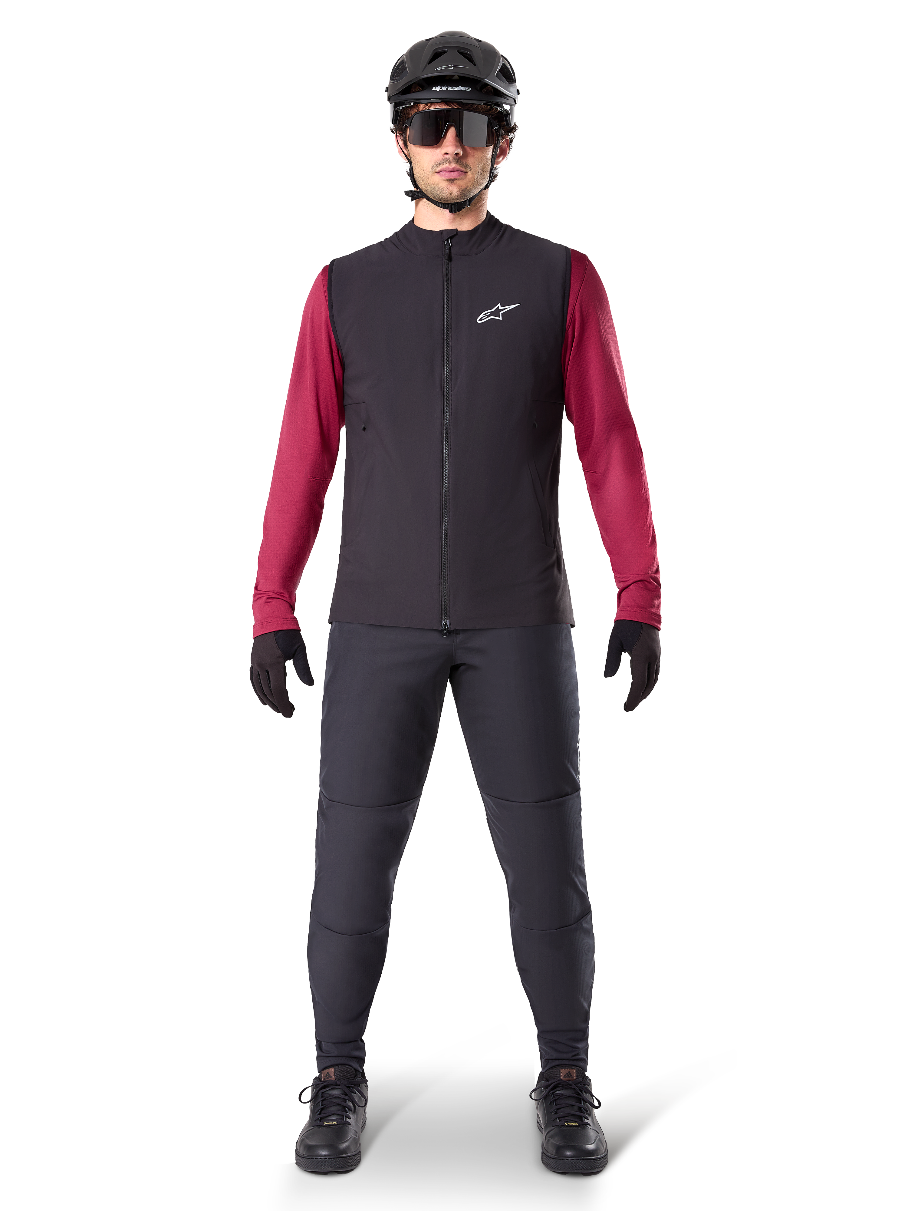 Alpinestars A-Dura värmeväst, svart cykelväst buren över en vinröd långärmad tröja, kombinerad med mörkgrå MTB-byxor, svart hjälm och solglasögon, teknisk mountainbike-utrustning för cykling i kallt väder