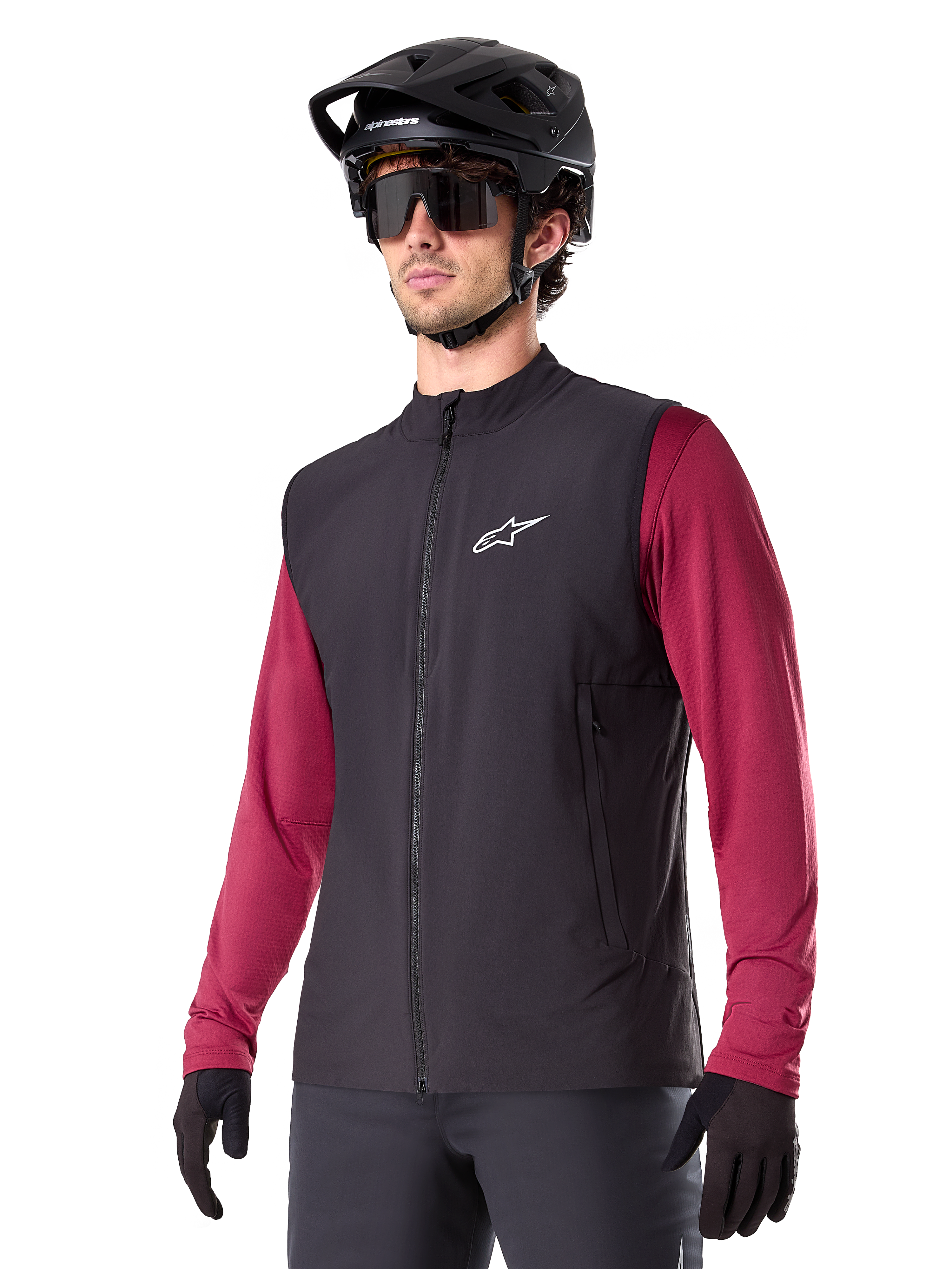 Alpinestars A-Dura Thermal Vest, svart, termisk cykelväst, bärs över en vinröd långärmad tröja, med en vit logotyp på bröstet, kombinerat med en svart MTB-hjälm och solglasögon, isolerande funktionslager för mountainbike