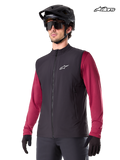 Alpinestars A-Dura Thermal Vest, men's mountain biking thermal vest in black, worn by a model with a helmet and a red long-sleeve jersey, insulation for cold-weather MTB riding