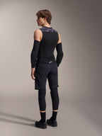 Manlig modell sedd bakifrån bär Alpinestars A-Motion Plasma skyddsväst, Black Camo, ärmlös mesh-design med integrerat ryggskydd, grått kamouflagemönster på axlarna, matchad med svarta armbågsskydd och mountainbike-shorts, professionell cykelutrustning