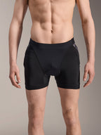 Alpinestars A-Motion Plasma Protection Boxers, MTB-skyddsshorts, svarta med svarta kamouflagedetaljer, framifrån på manlig modell, med ventilerande stretchmesh och integrerat höftskydd för cykelprestanda.