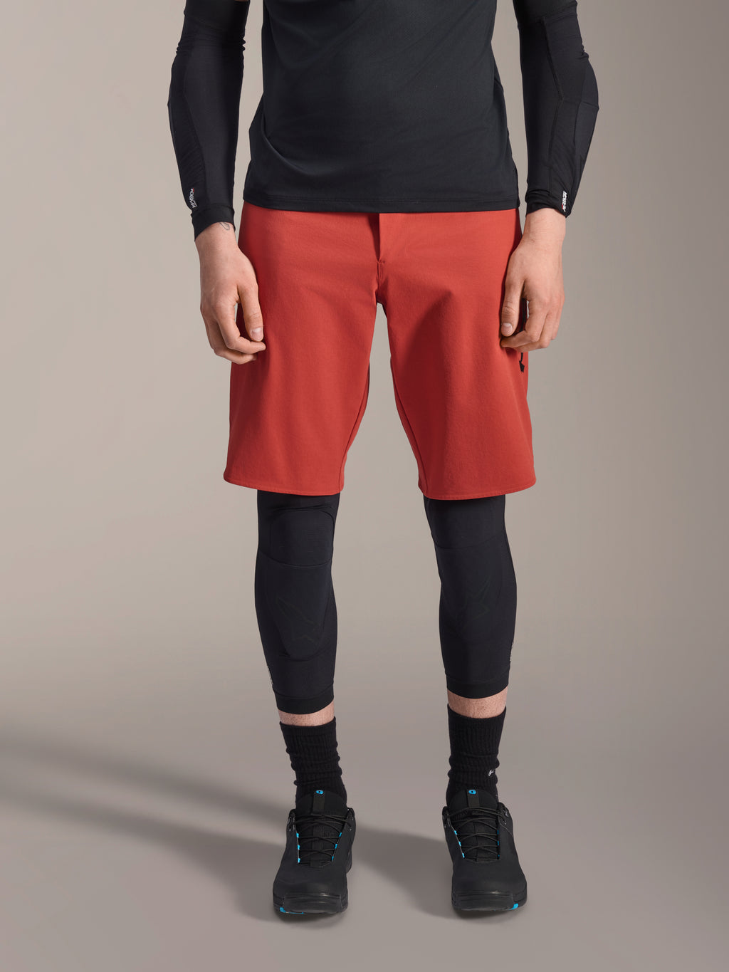 Alpinestars A-Motion Plasma Knee Sleeve, svarta knäskydd för MTB, bärs med röda shorts och svart långärmad tröja, ergonomisk design med smal profil, lättviktskonstruktion i mesh för terrängkörning