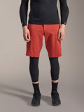 Alpinestars A-Motion Plasma Knee Sleeve, svarta knäskydd för MTB, bärs med röda shorts och svart långärmad tröja, ergonomisk design med smal profil, lättviktskonstruktion i mesh för terrängkörning