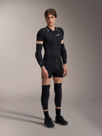 Manlig modell i Alpinestars A-Motion Plasma skyddsjacka – kortärmad, Black Camo med gråmönstrade axlar, centrerad dragkedja framtill och vit logotyp på bröstet, bärs med svarta arm- och knäskydd, teknisk MTB-skyddsutrustning för terrängkörning.