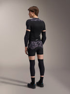 Modell som bär Alpinestars A-Motion Plasma skyddsboxershorts i Black Camo och matchande A-Motion Plasma skyddsjacka, vy bakifrån som visar grått kamouflagemönster, armbågsskydd, knäskydd och cykelskor, komplett uppsättning skyddsutrustning för mountainbike.