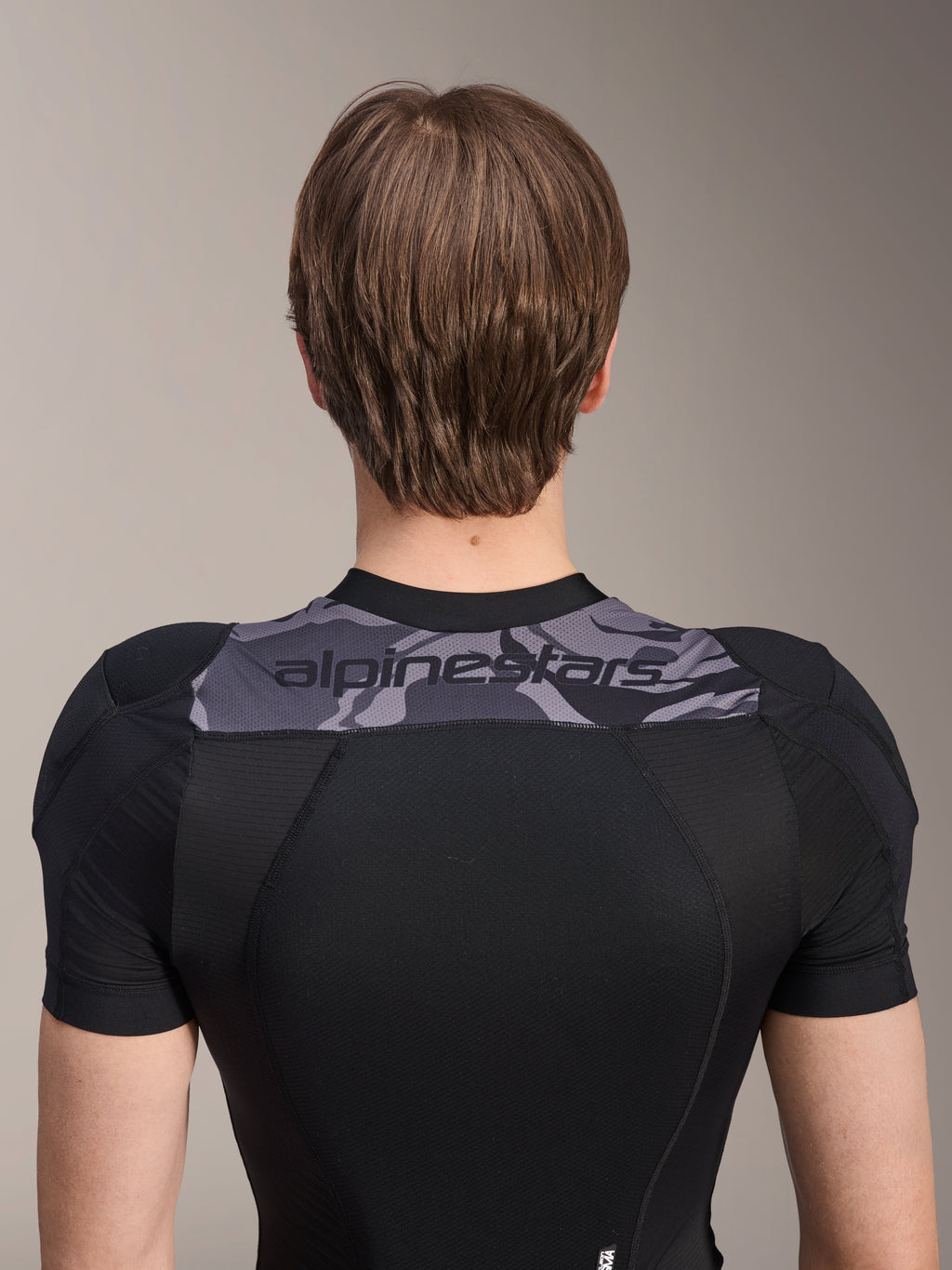 Alpinestars A-Motion Plasma skyddsjacka - kortärmad, baksida av överkroppen, svart med grå kamouflagepanel över axlarna och Alpinestars-logotyp, ventilerande stretchmesh-konstruktion för MTB-skydd