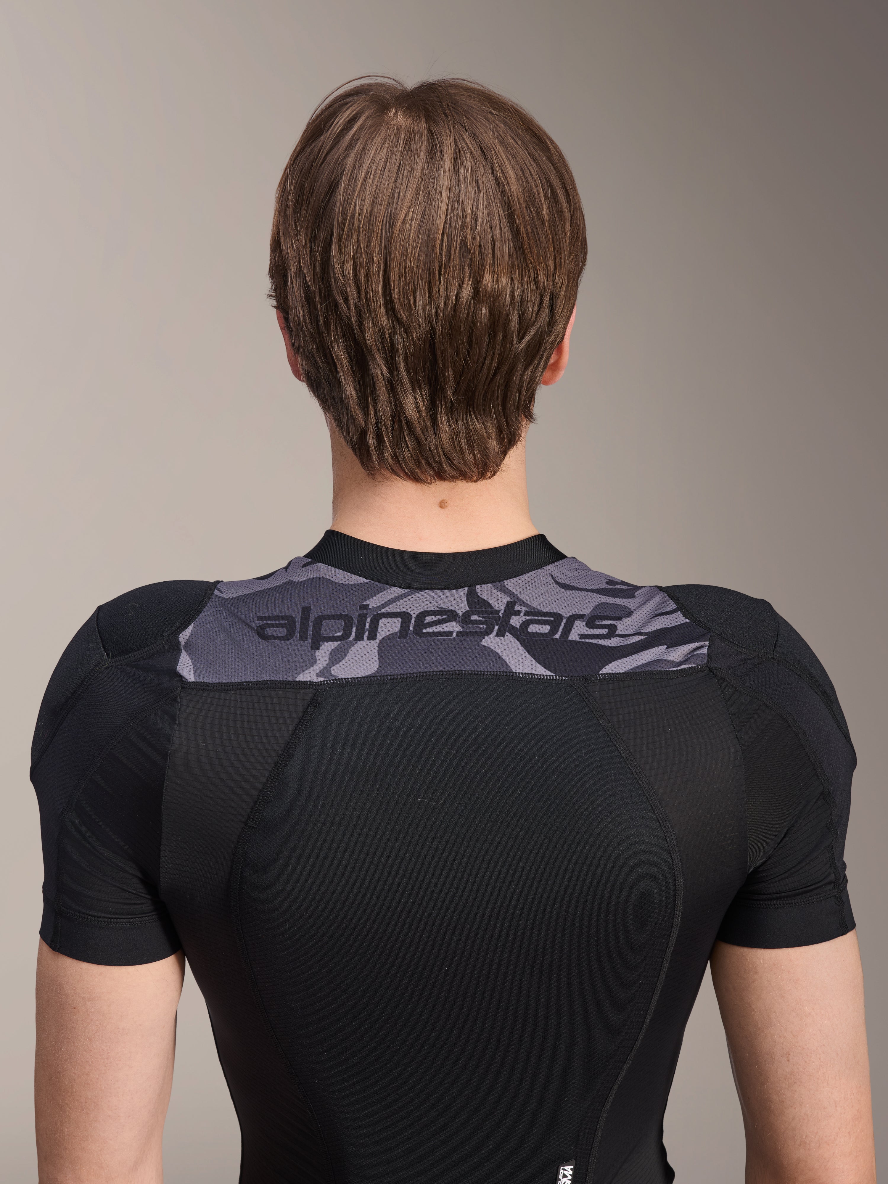 Alpinestars A-Motion Plasma skyddsjacka - kortärmad, baksida av överkroppen, svart med grå kamouflagepanel över axlarna och Alpinestars-logotyp, ventilerande stretchmesh-konstruktion för MTB-skydd