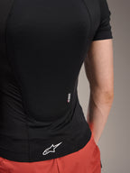 Alpinestars A-Motion Plasma skyddsjacka – kortärmad, Black Camo, detaljvy bakifrån som visar Nucleon PLASMA-märkning och vit Alpinestars-logotyp på nederkanten, ventilerande stretchmesh-konstruktion för MTB-skydd