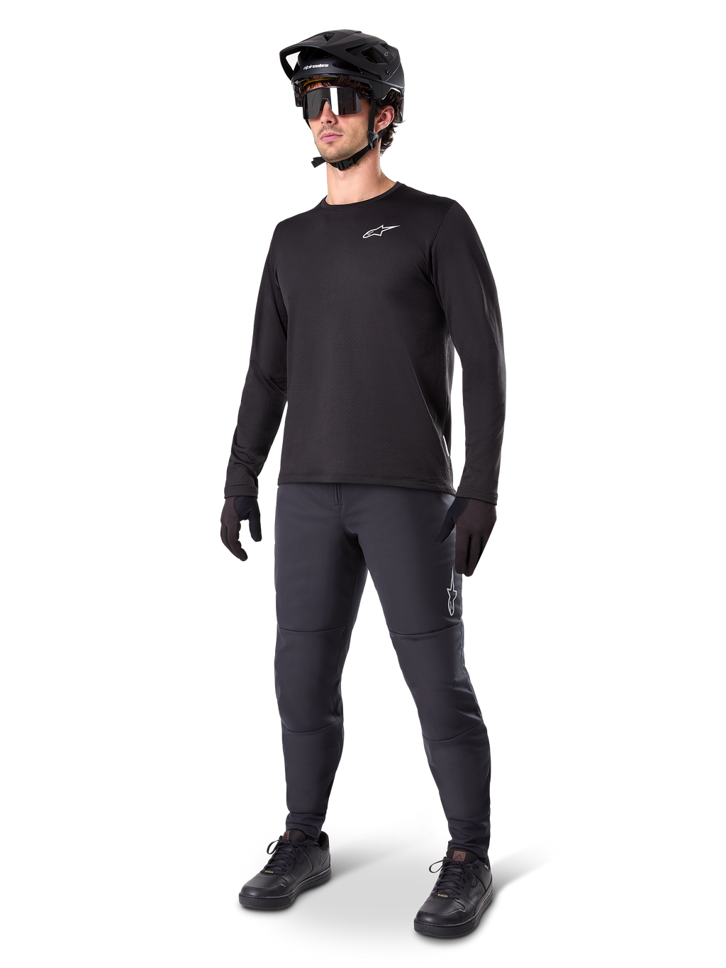 Mountainbike-cyklist iklädd Alpinestars A-Dura Thermal byxor, svarta, matchade med en svart långärmad tröja, svart hjälm och solglasögon, med en silverfärgad Alpinestars-logotyp på vänster lår, designade för terrängcykling i kallt väder