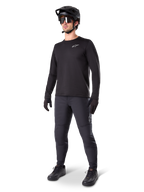 Mountainbike-cyklist iklädd Alpinestars A-Dura Thermal byxor, svarta, matchade med en svart långärmad tröja, svart hjälm och solglasögon, med en silverfärgad Alpinestars-logotyp på vänster lår, designade för terrängcykling i kallt väder