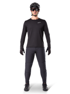 Alpinestars A-Dura Thermal Byxor, svarta, bärs av en cyklist i komplett mountainbike-utrustning inklusive en svart långärmad tröja, hjälm och solglasögon, slitstarka byxor med normal passform för stigcykling i kallt väder