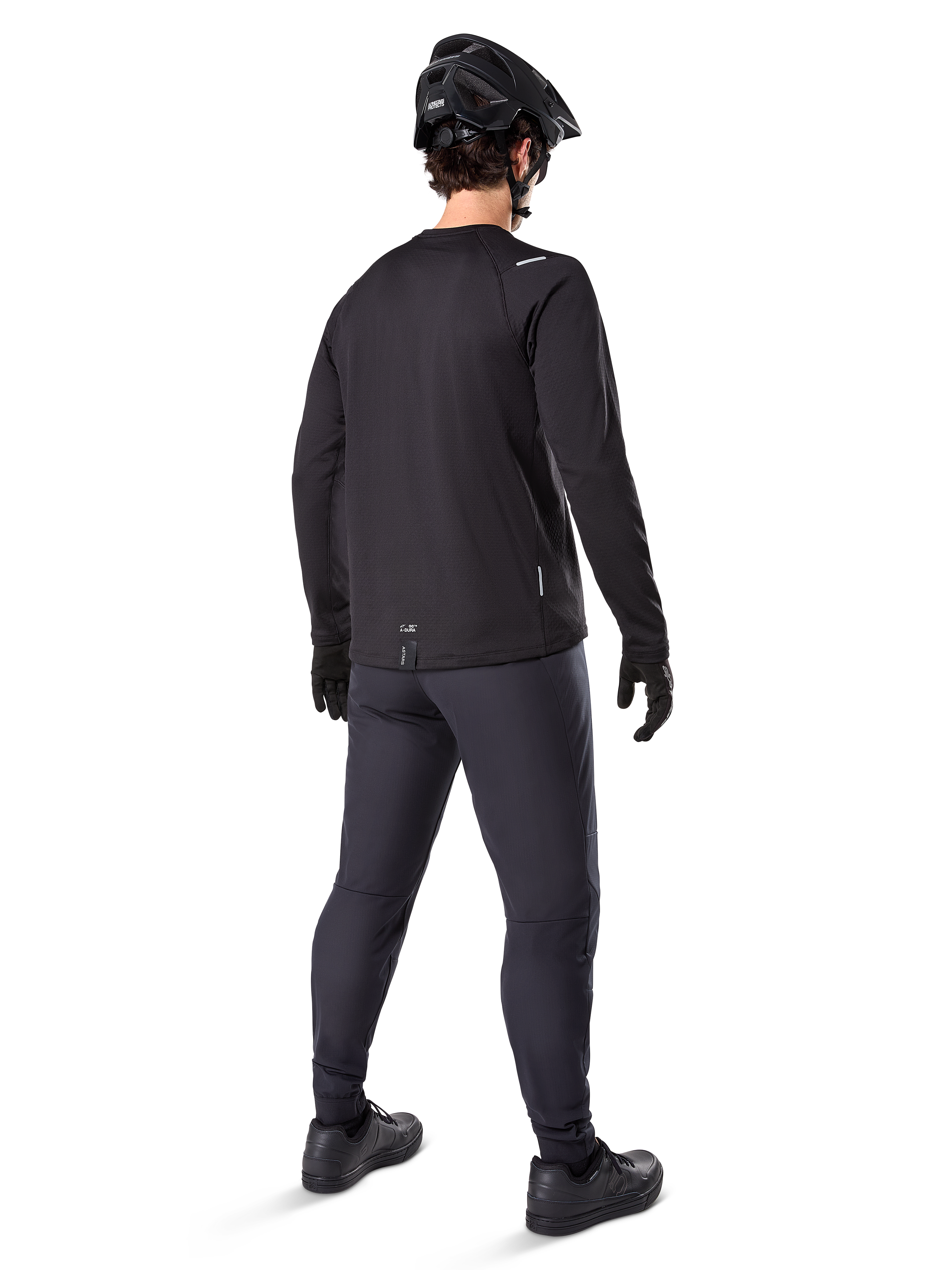 Alpinestars A-Dura Thermal Byxa, mountainbikebyxor, svarta, sedda bakifrån bärs med en matchande långärmad tröja, svart MTB-hjälm och handskar, teknisk cykelutrustning för kallt väder