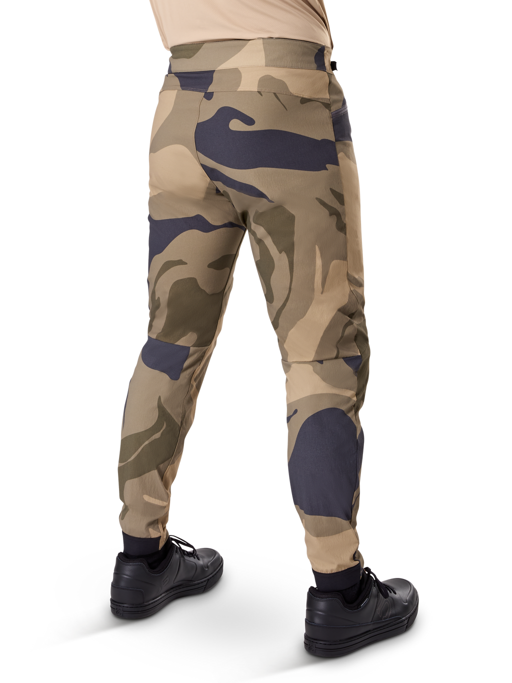 Alpinestars A-Dura Camo Pant, MTB-byxor, brunt kamouflagemönster med beige och mörkgrå detaljer, sedda bakifrån med svarta sneakers, avsmalnande ben och elastiska muddar, slitstarkt 2-vägs stretchmaterial för mountainbike