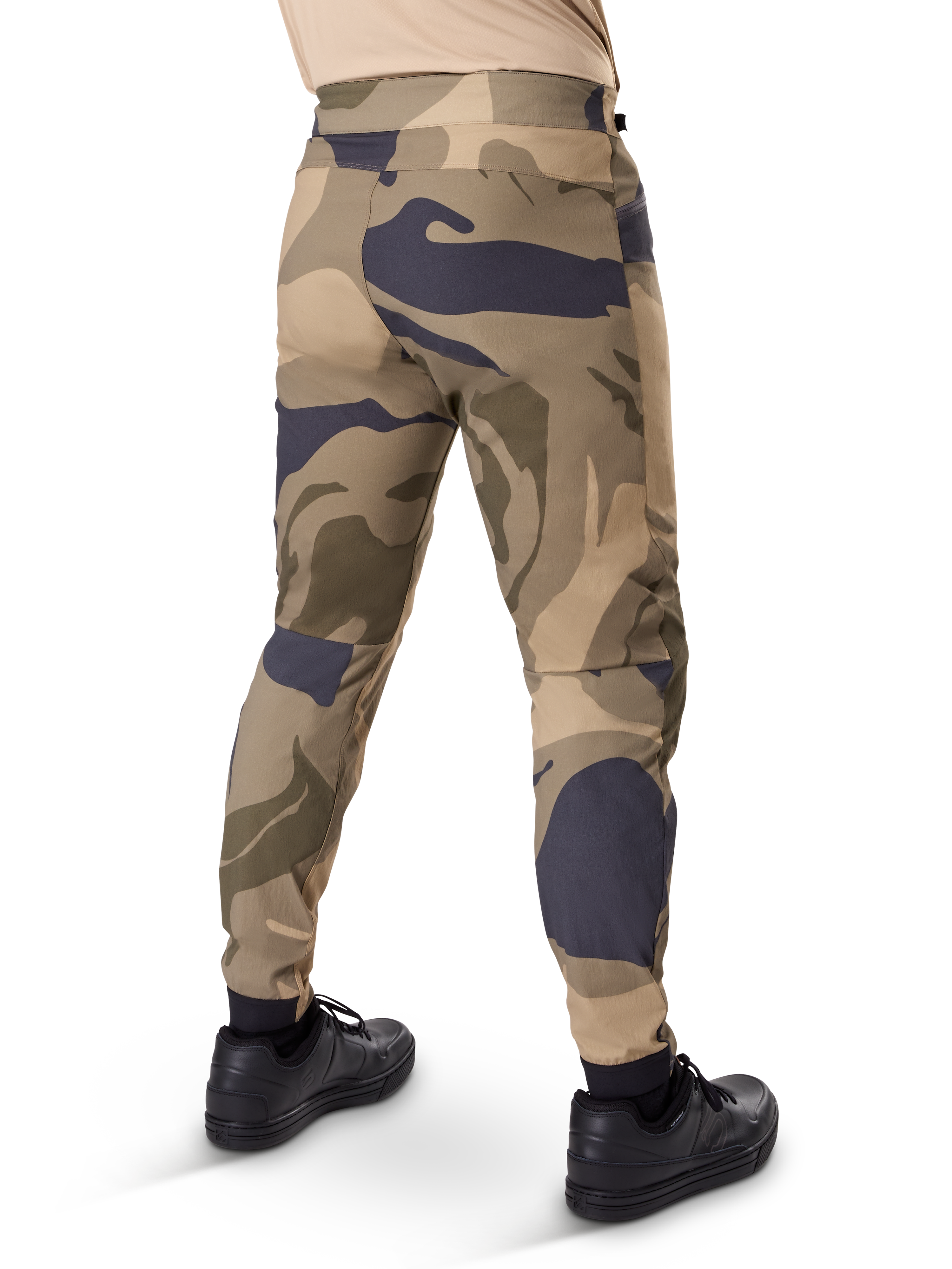 Alpinestars A-Dura Camo Pant, MTB-byxor, brunt kamouflagemönster med beige och mörkgrå detaljer, sedda bakifrån med svarta sneakers, avsmalnande ben och elastiska muddar, slitstarkt 2-vägs stretchmaterial för mountainbike